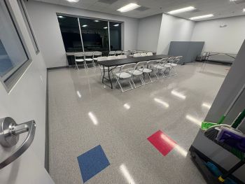 Office cleaning services in a conference room with polished floors, folding tables, chairs, and cleaning supplies